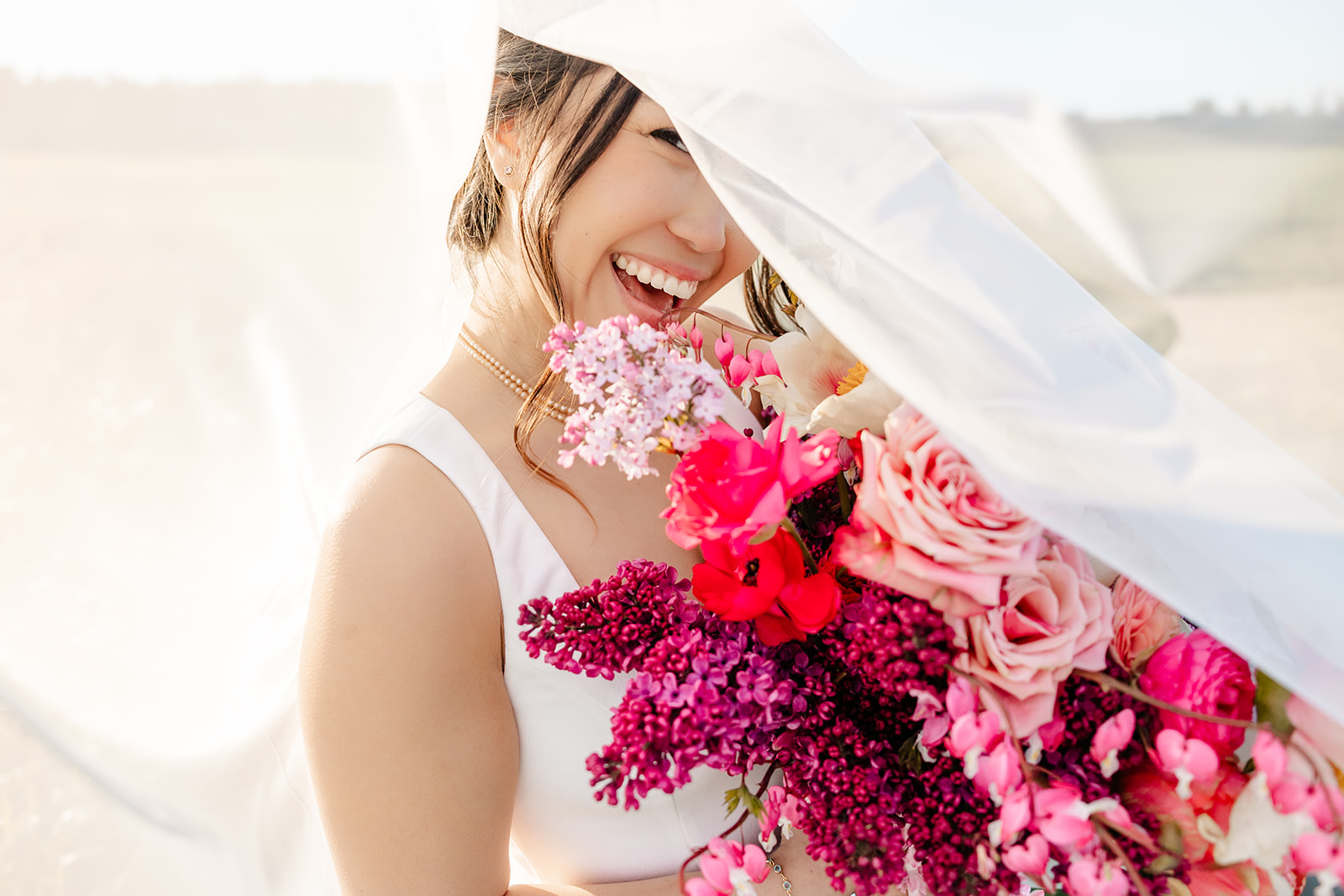 girl peeks from a veil with pink flowers