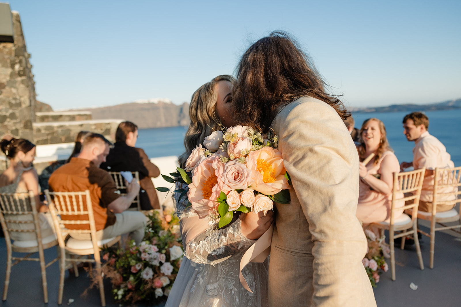 bride holds bouquet as she and groom kiss at end of aisle