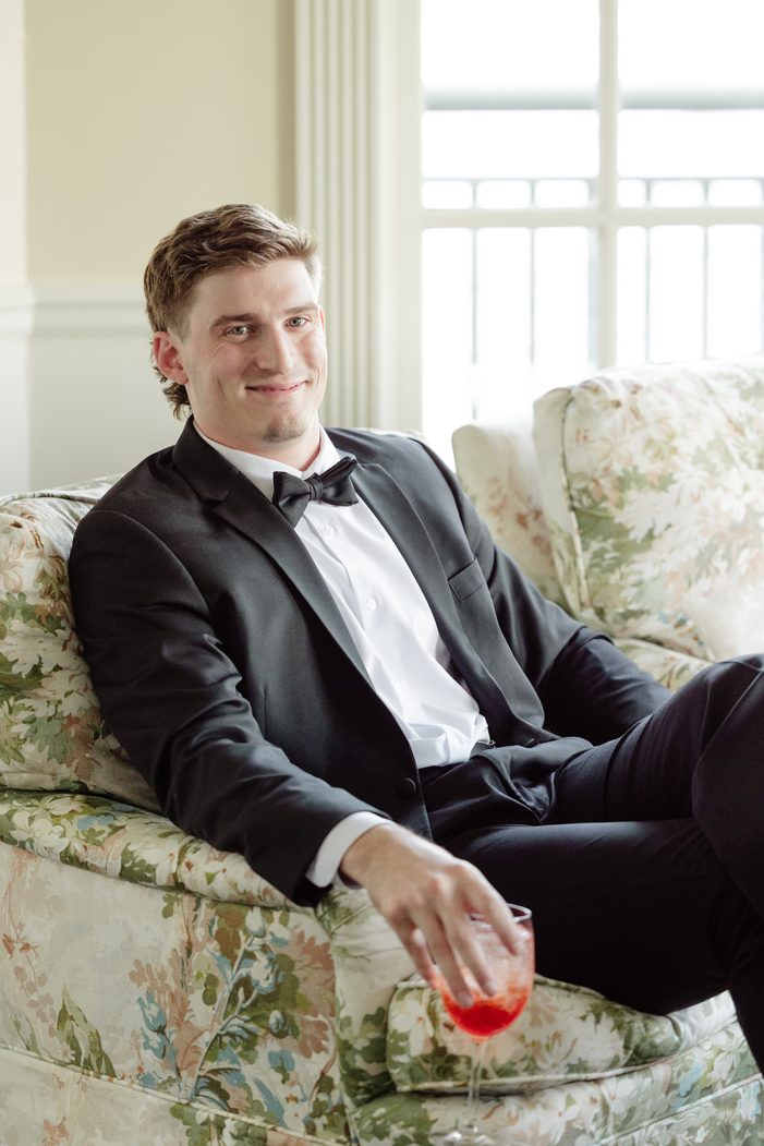 man in a suit sits in a floral chair
