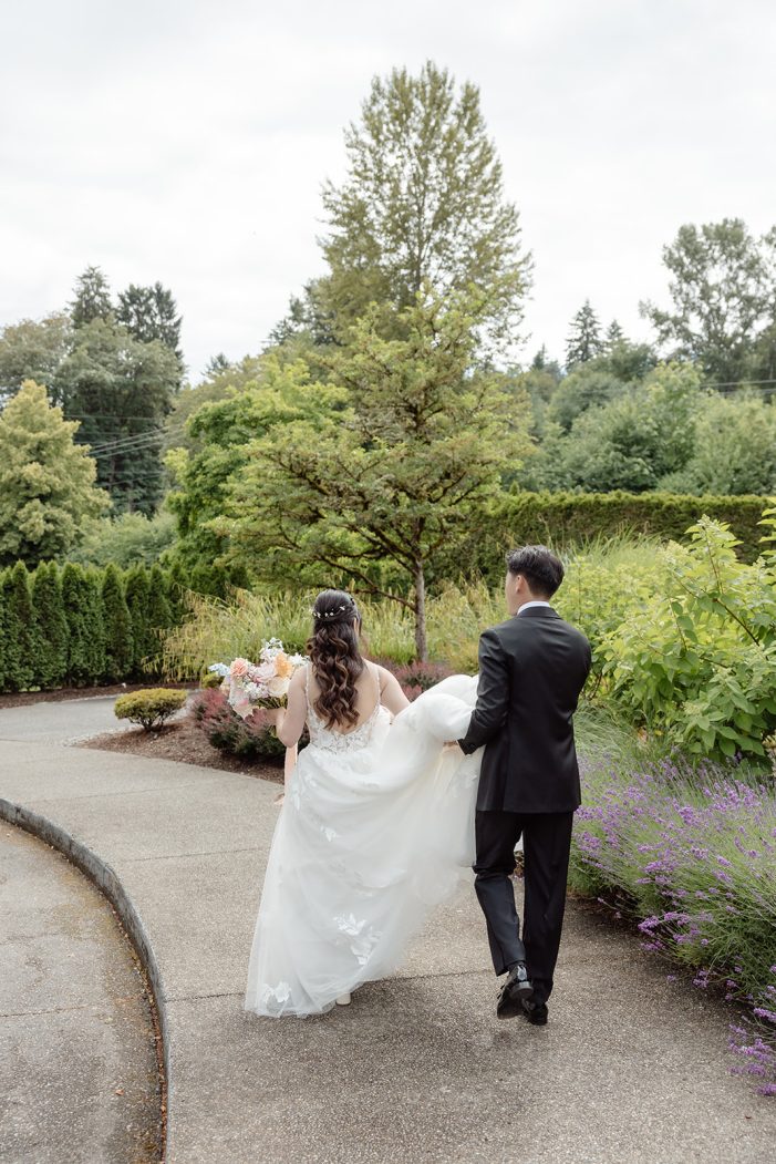 bride and groom walk through gardens